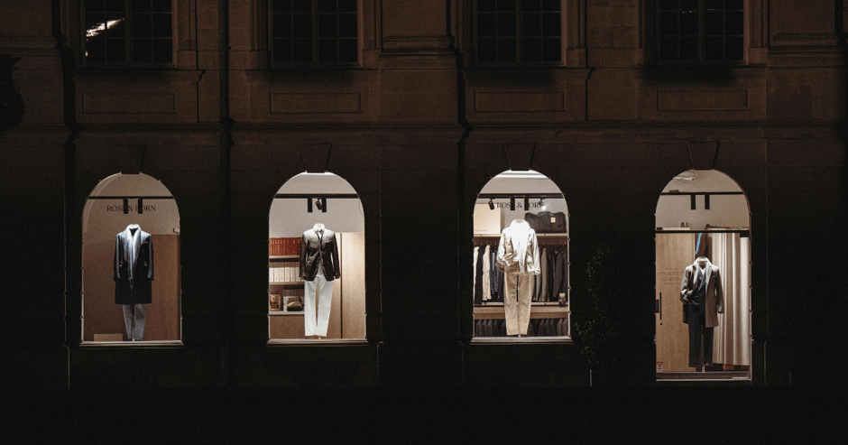 Exterior shot of a luxury retail store's suit window display at night